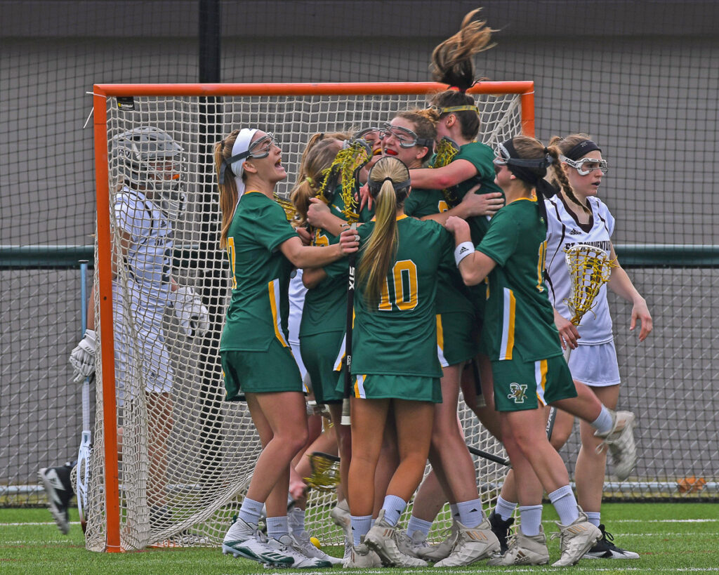 University of Vermont Women's Lacrosse team celebrating in front of net during win against St. Bonaventure University Bonnies