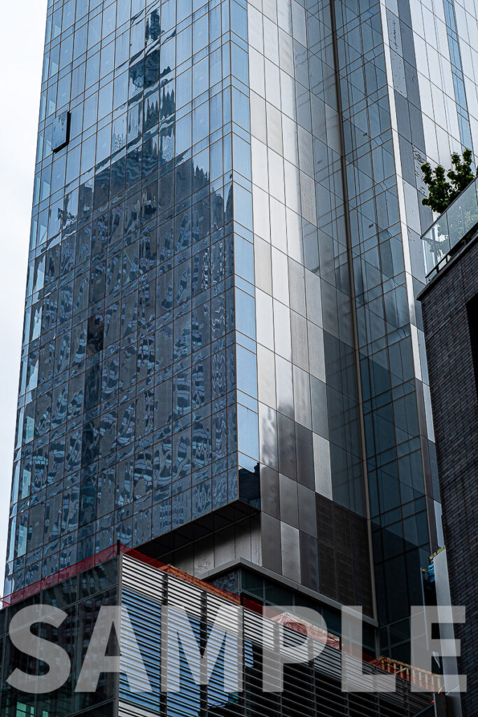 Empire State Building reflected in glass building on 7th Avenue in New York City.  Photo copyright 2021 by Paul Barretta